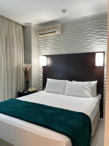 ein Schlafzimmer mit einem großen Bett und einer grünen Decke in der Unterkunft Flat TRIANGULO DAS BERMUDAS Home Experience Praia do Canto in Vitória