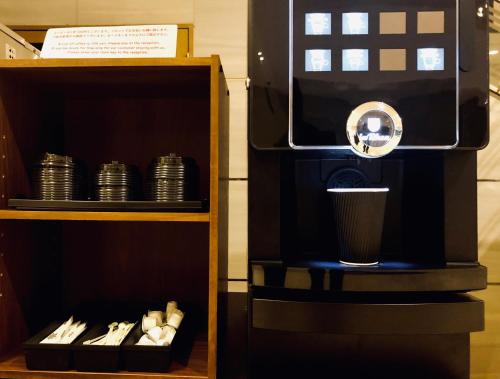 a coffee machine with a cup on a shelf at ART Hotel Oita in Oita