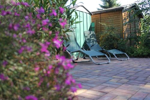 three chairs sitting on a patio with purple flowers at Spreewaldhäuser am See in Alt Schadow