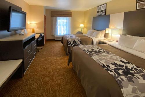 a hotel room with two beds and a flat screen tv at Sleep Inn & Suites Springdale West in Springdale