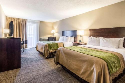 Habitación de hotel con 2 camas y escritorio con lámparas en Comfort Inn, en Lansing