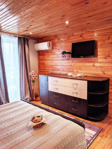 a bedroom with a bed and a flat screen tv at Котедж-парк Славна in Okhtyrka