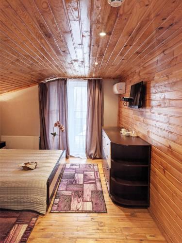 a bedroom with a bed and a dresser and a television at Котедж-парк Славна in Okhtyrka