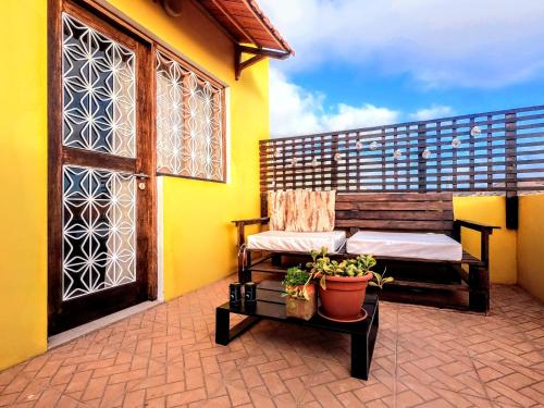 einen Balkon mit einer Bank, einer Tür und einer Pflanze in der Unterkunft Casa Bom Dia in Mindelo