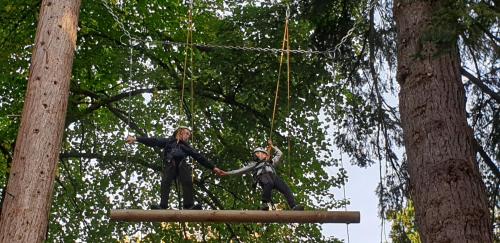 a man and a woman riding on a swing in the trees at Fairburn Activity Centre in Contin