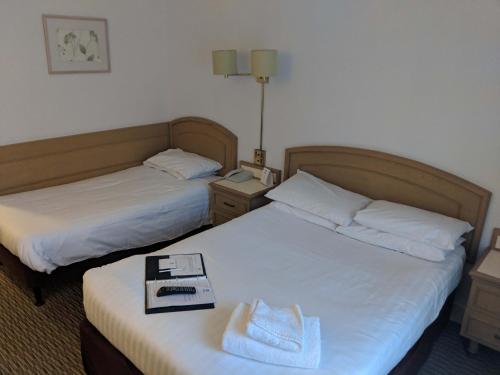 two beds in a hotel room with a tray on the bed at Best Western Ipswich Hotel in Ipswich