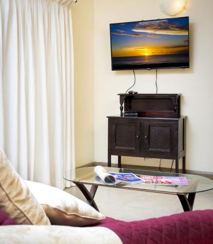 a living room with a coffee table and a flat screen tv at Ground floor apartment located in Hometown, 5 min walk to the Beach in Saint James