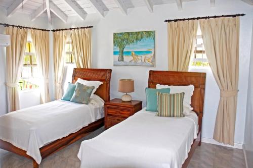 two beds in a room with two windows at Silver Sands Beach Villas are great for family-friendly activities surfing in Christ Church