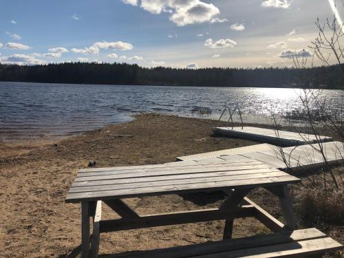 a picnic table sitting on the shore of a lake at Paradiset stugan i fin skogen in Hällefors