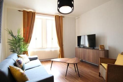 a living room with a couch and a tv at Appartements Le Cru Colbert in Beaune