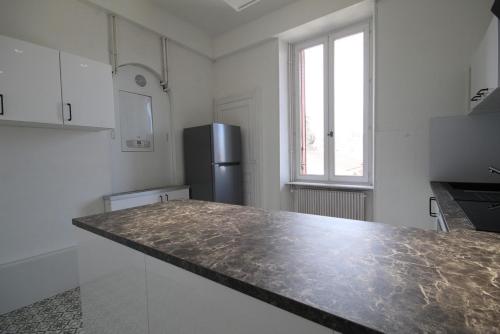 a kitchen with a counter top and a refrigerator at Appartements Le Cru Colbert in Beaune