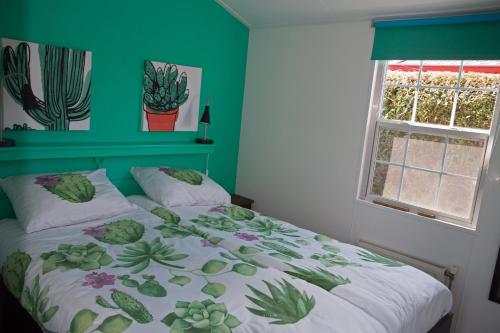 Un dormitorio con una cama con una pared verde. en dutchduochalet37, en s-Gravenzande