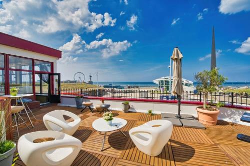 a patio with white chairs and a view of the ocean at Strandhotel Scheveningen in Scheveningen