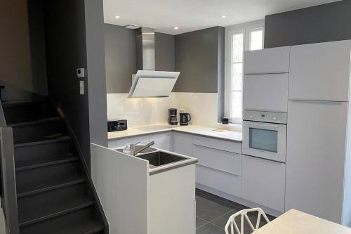 une cuisine blanche avec un évier et une cuisinière dans l'établissement LE CHAT BOTTE / Superbe maison de ville au cœur du Touquet!, à Le Touquet-Paris-Plage