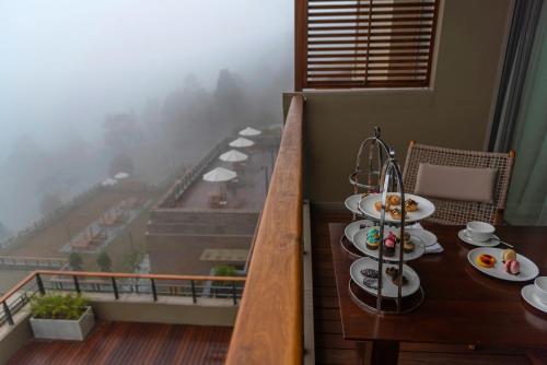 a balcony with a table with plates of food on it at Taj Chia Kutir Resort & Spa Darjeeling in Darjeeling