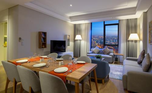 a dining room and living room with a table and chairs at Movenpick Living Istanbul West in Istanbul