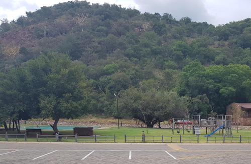 a park with a playground with trees and a mountain at ATKV Klein-Kariba in Bela-Bela