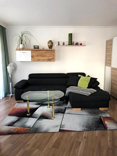 a living room with a black couch and a glass table at Apartments an der Caracalla Therme in Baden-Baden