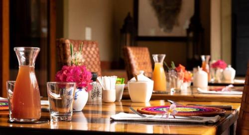 a wooden table with plates and glasses and flowers on it at Villa Chad Luxury Guesthouse in Kleinmond