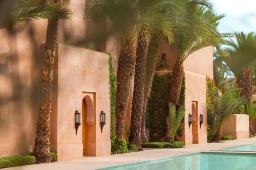 a resort with palm trees and a swimming pool at Amanjena Resort in Marrakech
