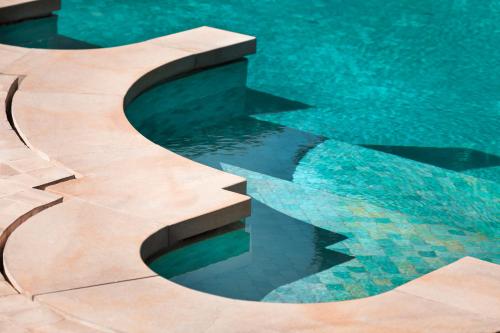 a swimming pool with a wooden curve in the water at Amanjena Resort in Marrakech
