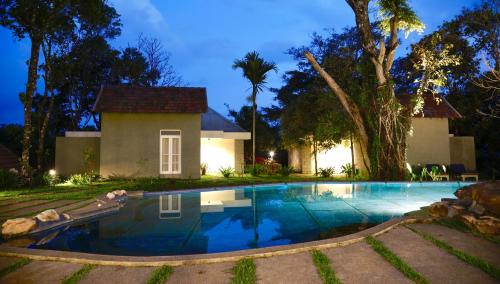 a swimming pool in front of a house at night at SpiceTree Rajakumari in Munnar