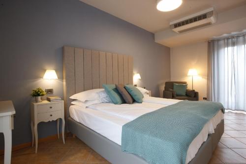 a bedroom with a large white bed with blue pillows at Hotel Milano & Apartments in Miazzina