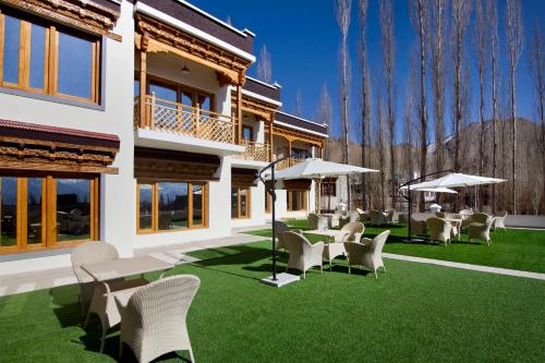 a yard with chairs and tables and umbrellas at Hotel Paradise Ladakh in Leh