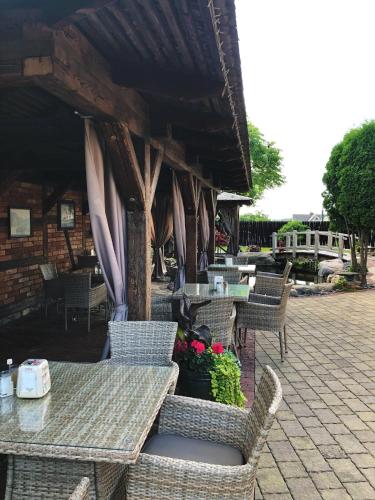 an outdoor patio with wicker chairs and tables and flowers at Senoji užeiga in Molėtai