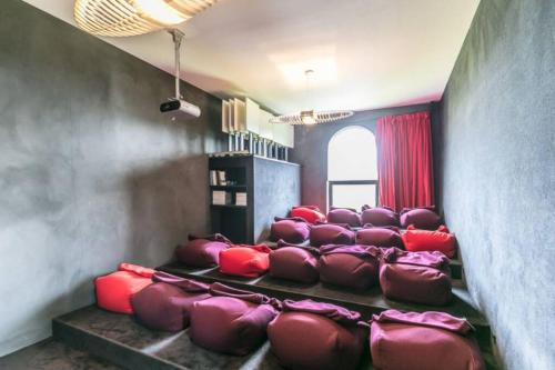a theater room with a bunch of red chairs at La Classe - Former school of the village of Denée in Denée