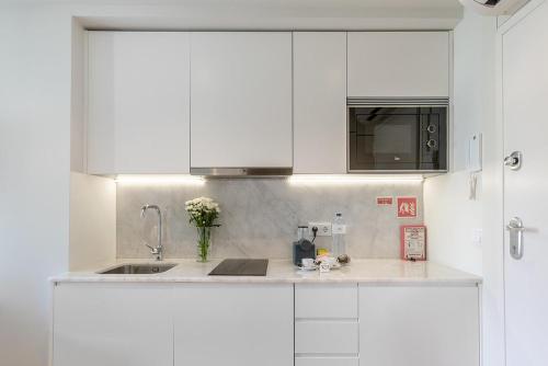 Una cocina con gabinetes blancos y un fregadero. en Inside Porto Apartments - Pinheiro, en Oporto