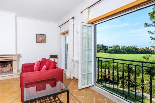 a living room with a red couch and a fireplace at Maravilhoso T1 Praia D'el Rey in Amoreira