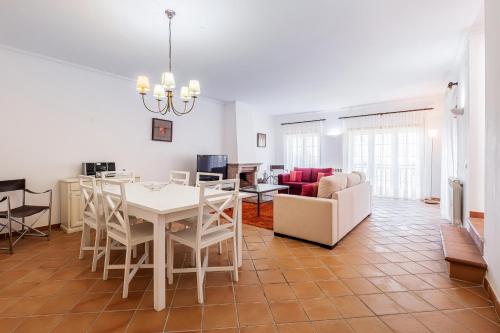 a dining room and living room with a white table and chairs at Maravilhoso T1 Praia D'el Rey in Amoreira