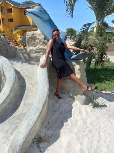 a woman in a black dress standing next to a slide at Golden Duranta Villas in Ukunda