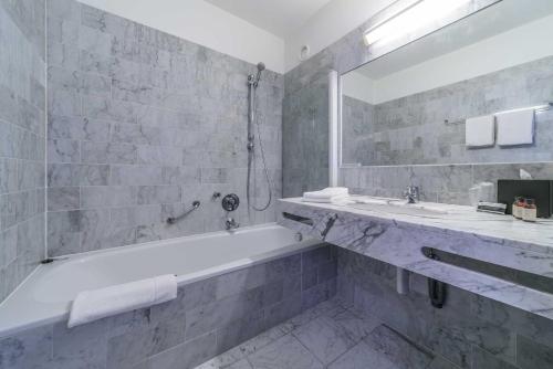 a white bathroom with a tub and a sink at Cosmopolite Hotel Nieuwpoort-Bad in Nieuwpoort