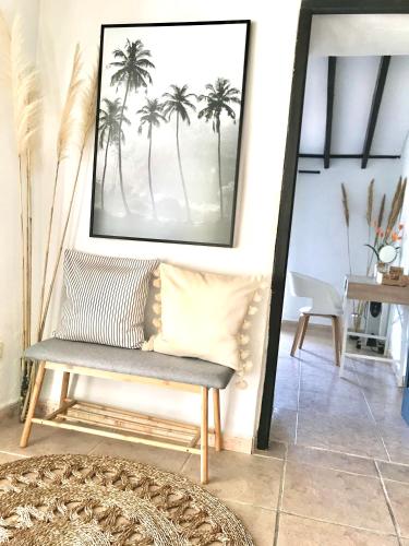 a bench in a living room with a picture of palm trees at Casa Hector in Granada