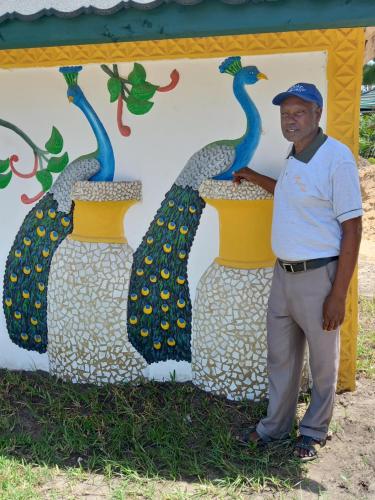 a man standing in front of a large painting of peacocks at Golden Duranta Villas in Ukunda