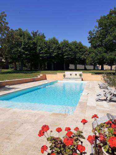 une piscine avec des fleurs rouges devant dans l'établissement Chateau des Poccards, à Hurigny