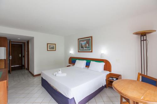a bedroom with a large white bed and a table at Samba Angra dos Reis in Angra dos Reis