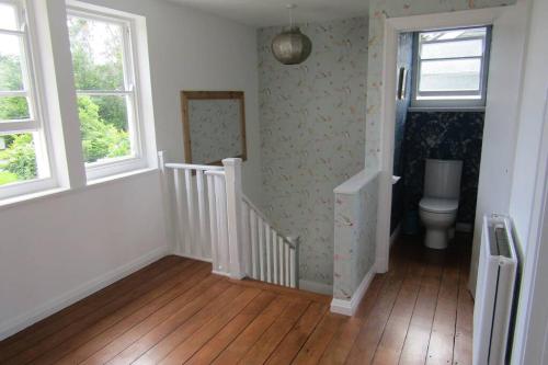 a bathroom with a toilet and a staircase with windows at Lovely 3 Bed House Close to Carlyon Bay Beach! in Carlyon Bay