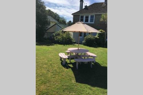 a picnic table with an umbrella and two benches at Lovely 3 Bed House Close to Carlyon Bay Beach! in Carlyon Bay