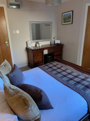 a bedroom with a bed with a desk and a mirror at Beaufort Hotel in Inverness