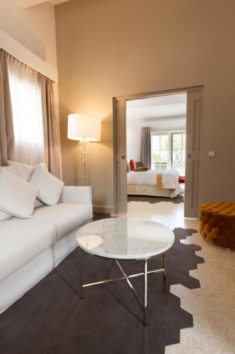 a living room with a white couch and a table at Mas des Herbes Blanches Hôtel & Spa – Relais & Châteaux in Joucas