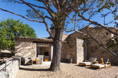 a patio with chairs and a tree in front of a building at Mas des Herbes Blanches Hôtel & Spa – Relais & Châteaux in Joucas