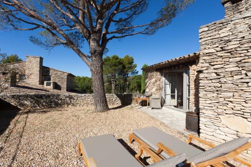a stone building with a tree and some chairs at Mas des Herbes Blanches Hôtel & Spa – Relais & Châteaux in Joucas