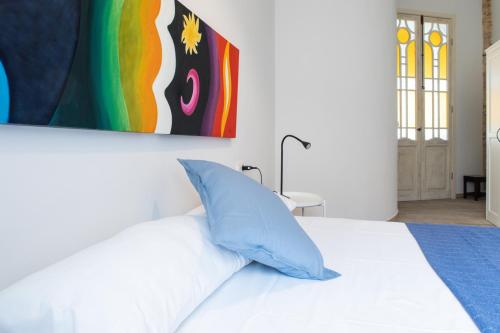 a bedroom with a white bed with a blue pillow at Traditional Valencian Townhouse in Catarroja in Catarroja