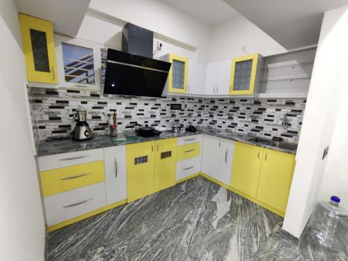 a kitchen with yellow cabinets and a flat screen tv at Vogel's Nest in Mysore