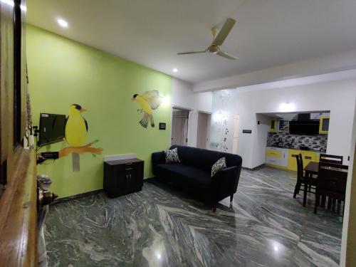 a living room with a couch and birds painted on the wall at Vogel's Nest in Mysore