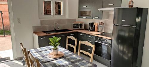 Il comprend une cuisine équipée d'une table et d'un réfrigérateur noir. dans l'établissement Casevielle le calme en Provence, à Tulette