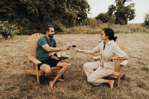 un homme et une femme assis à une table avec des verres à vin dans l'établissement Parcel Tiny House I Saint Emilion, à Saint-Émilion